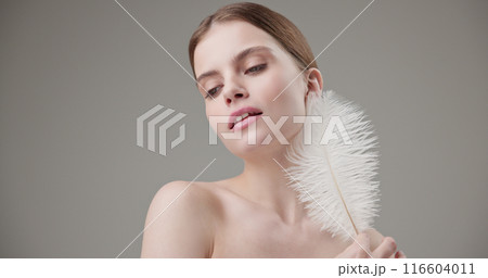 Beauty, health, cosmetics, anti-aging therapy and skin care concept - young beautiful brunette Caucasian woman holding a white fluffy feather in her hands, tenderness, lightness and softness Beauty, health, cosmetics, anti-aging therapy and skin care concept - young beautiful brunette Caucasian woman holding a white fluffy feather in her hands, tenderness, lightness and softness 116604011