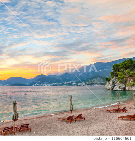 Captivating sunset at beach with chaise lounges and umbrellas in Sveti Stefan near Budva. Captivating sunset at beach with chaise lounges and umbrellas in Sveti Stefan near Budva. 116604661