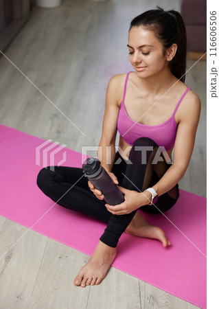 sporty athletic fitness woman in sportswear holding water bottle at home, top view sporty athletic fitness woman in sportswear holding water bottle at home, top view 116606506