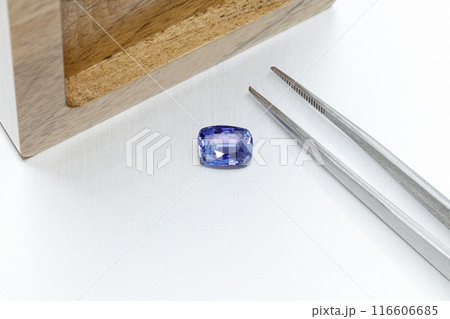 macro mineral faceted stone sapphire with tweezers on a gray background 116606685