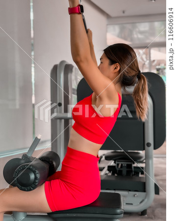 Woman in red sportwear working out in the gym. 116606914