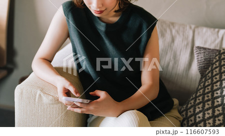 ソファでスマホを使う笑顔の日本人女性 ソファでスマホを使う笑顔の日本人女性 116607593