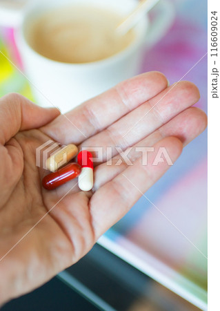 Close up of caucasian female hand with pills at breakfast Close up of caucasian female hand with pills at breakfast 116609024