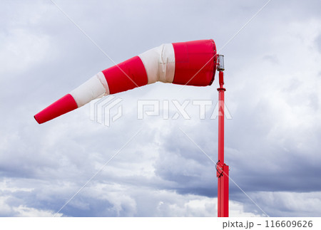 Red and white weather vane and dramatic cloudy sky. 116609626