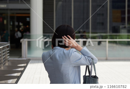夏のオフィス街で電話する一人の女性営業マンの姿 夏のオフィス街で電話する一人の女性営業マンの姿 116610782
