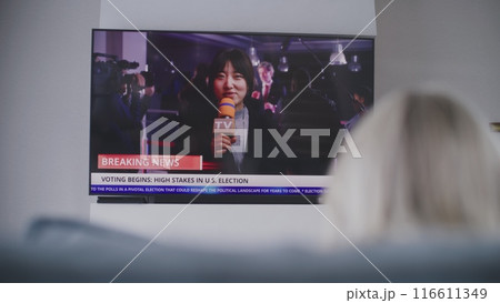 Woman rests on couch, watches breaking news on Election Day 116611349