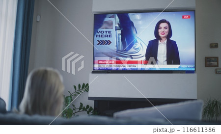 Adult woman watches TV news about elections in USA Adult woman watches TV news about elections in USA 116611386
