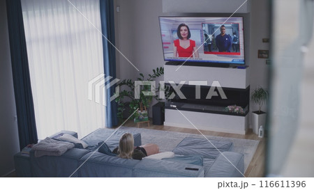 Young girl comes into room and sits on sofa near mother 116611396