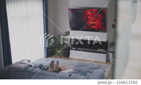 Caucasian woman rests, watches TV and uses mobile phone Caucasian woman rests, watches TV and uses mobile phone 116611592