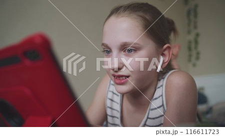 Beautiful teenager in headphones lies on bed in her room 116611723