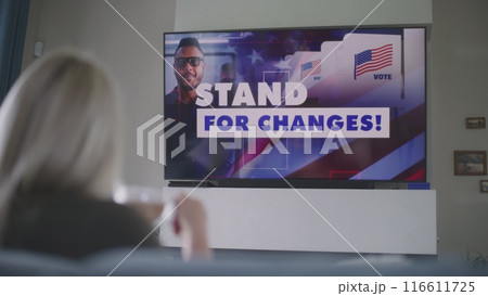 Woman watches political advertising about US elections on TV 116611725