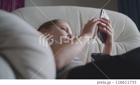 Caucasian teenager uses her mobile phone to chat with friends Caucasian teenager uses her mobile phone to chat with friends 116611735