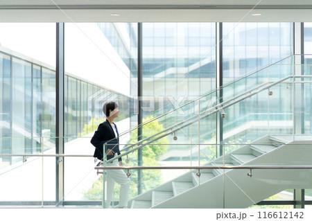 オフィスビルの中を歩くスーツの女性 116612142