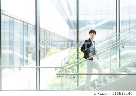 オフィスビルの中を歩くスーツの女性 オフィスビルの中を歩くスーツの女性 116612146