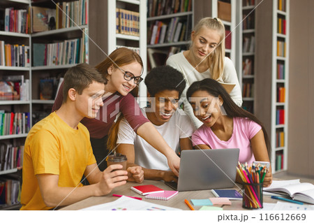 Multinational Team Of College Students Talking Over Project, girl pointing at laptop screen, library interior 116612669