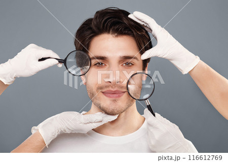 Rejuvenation and skin care. Face of young handsome man with beautician's hands and magnifiers 116612769