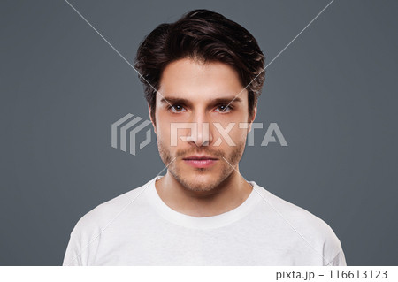 Confident man. Young millennial guy seriously looking at camera, grey background 116613123