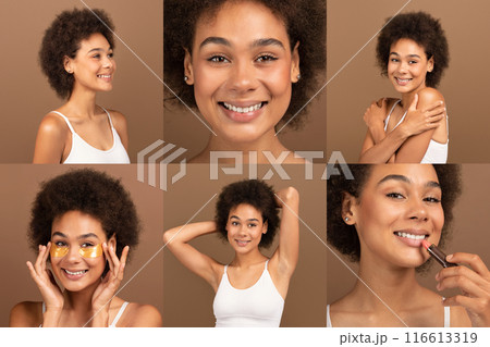 African American young woman with dark skin and a large hairstyle is photographed in a studio setting. She is smiling and applying makeup in different poses. The background is a brown wall 116613319