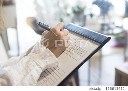 美容サロンで問診票を記入する若い女性手元 美容サロンで問診票を記入する若い女性手元 116613612