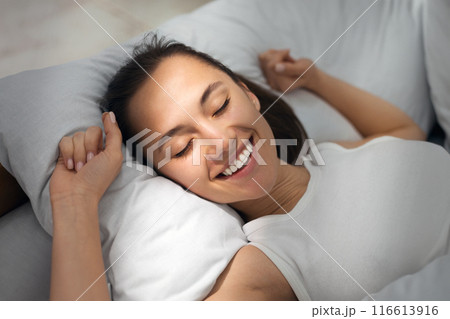 Happy morning. Woman waking up and stretching, lying in bed comfortably and blissfully 116613916