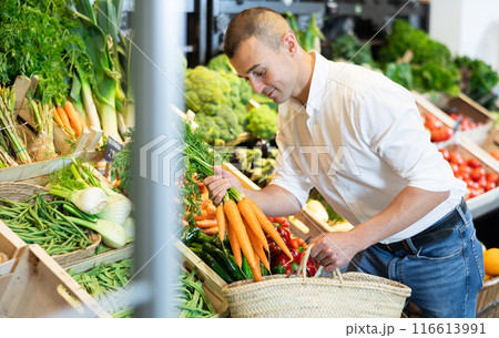 Young man purchaser buying organic carrot in grocery store 116613991