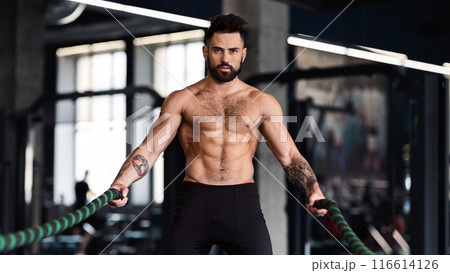 Muscular guy with naked torso exercising with battle ropes, crossfit training concept 116614126