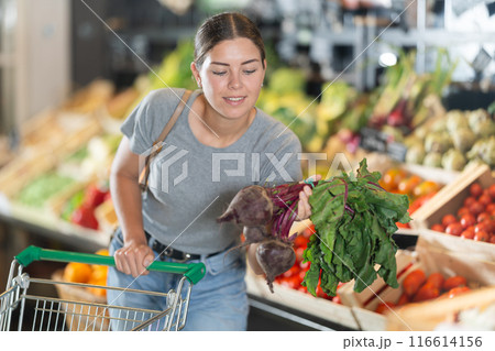 In vegetable department of bio supermarket, female customer took bunch of beets from window In vegetable department of bio supermarket, female customer took bunch of beets from window 116614156
