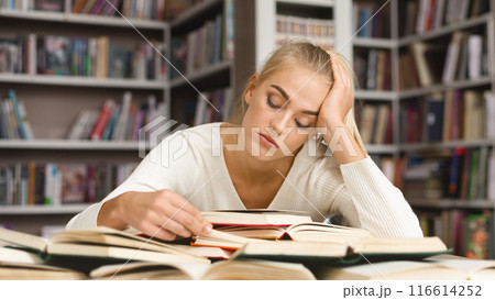 Super Tired Caucasian Girl Reading Book, leaning on her elbow, library interior 116614252