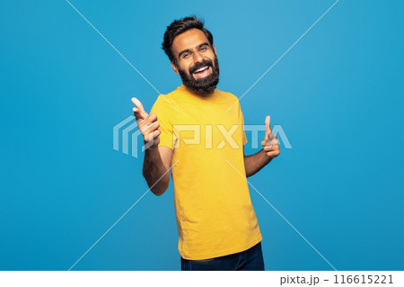 Indian man wearing a yellow t-shirt is enthusiastically giving a thumbs up gesture, showing approval or agreement. He appears to be smiling and expressing positivity or encouragement. 116615221