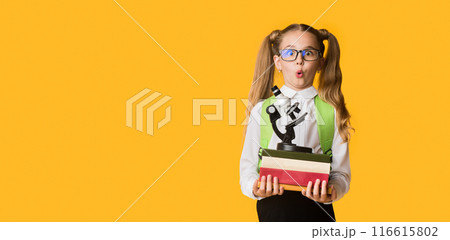 Back To School. Surprised First-Grade Schoolgirl Holding Stack Of Heavy Books And Microscope On Yellow Background. Copy Space Back To School. Surprised First-Grade Schoolgirl Holding Stack Of Heavy Books And Microscope On Yellow Background. Copy Space 116615802