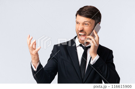Phone Rage. Furious Businessman Shouting Talking On Cellphone Over White Studio Background, free space Phone Rage. Furious Businessman Shouting Talking On Cellphone Over White Studio Background, free space 116615900