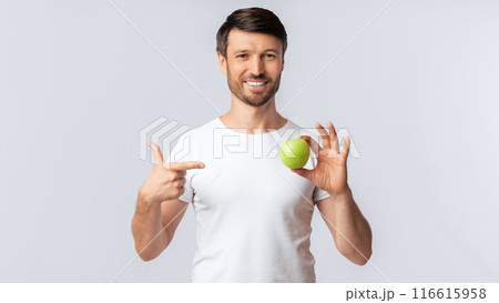 Healthy Diet. Smiling Man Pointing Finger At Apple In His Hand Standing Over White Studio Background. Panorama, Empty Space Healthy Diet. Smiling Man Pointing Finger At Apple In His Hand Standing Over White Studio Background. Panorama, Empty Space 116615958