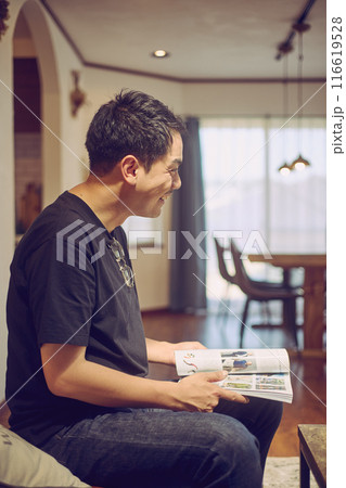 ソファーで本を読みながらくつろぐ若い男性 116619528