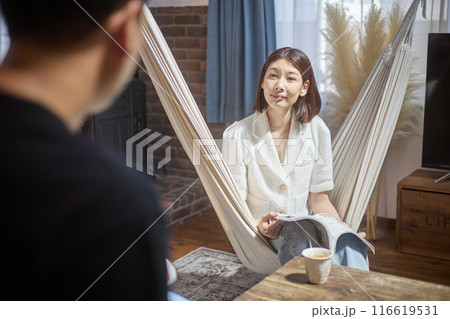 リビングでくつろぎながら会話する夫婦 リビングでくつろぎながら会話する夫婦 116619531