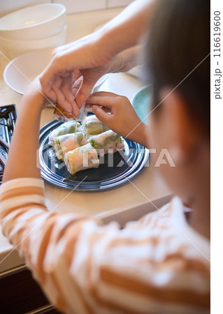 惣菜の盛りつけをする母と息子 116619600