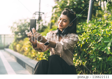 Asian woman using smartphone enhance self love relax sitting at garden 116622111