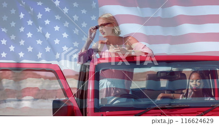 Image of flag of usa over african american and caucasian female friends sitting in car 116624629