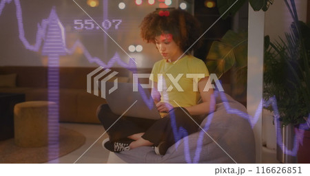 A biracial woman is shown working in a creative office, sitting on a bean bag with her legs crossed A biracial woman is shown working in a creative office, sitting on a bean bag with her legs crossed 116626851