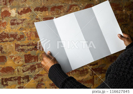 Biracial man examines a blank brochure, with copy space 116627845