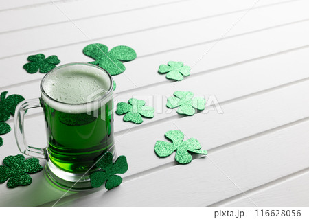 Image of glass with green beer, clover and copy space on white wooden background Image of glass with green beer, clover and copy space on white wooden background 116628056