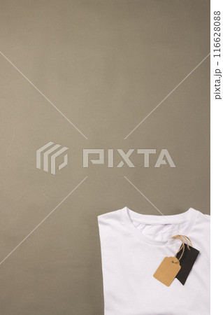 A white t-shirt with a blank tag lies on a plain background, with copy space A white t-shirt with a blank tag lies on a plain background, with copy space 116628088
