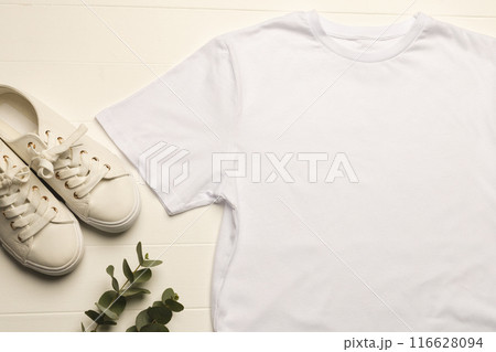 White t-shirt and sneakers on wood with plant for minimalist fashion promo. White t-shirt and sneakers on wood with plant for minimalist fashion promo. 116628094
