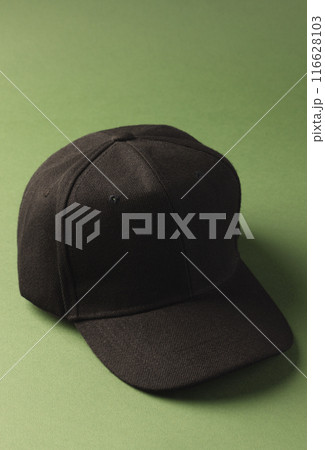 A black baseball cap is positioned against a green background, with copy space A black baseball cap is positioned against a green background, with copy space 116628103