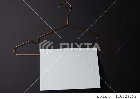 A blank white card hangs on a copper hanger against a dark background with copy space A blank white card hangs on a copper hanger against a dark background with copy space 116628258