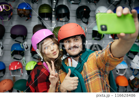 Joyful loving couple taking selfie photo in protective bicycle helmet Joyful loving couple taking selfie photo in protective bicycle helmet 116628486
