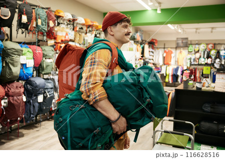 Satisfied man traveler going to cashier counter desk to pay for purchases 116628516