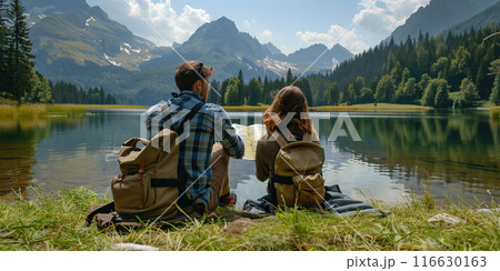 Beautiful young tourist couple with map looking at the mountain lake. Summer trip in nature. Lifestyle, togetherness, active life concept. Travelers with backpacks relaxing after hiking. Tourism 116630163
