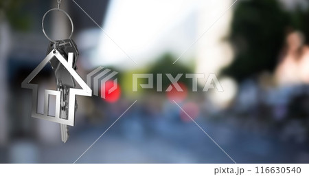 Image of hanging silver house keys against blurred view of city traffic with copy space 116630540