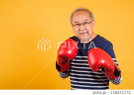 Portrait Asian old man wearing glasses wear two red boxing gloves studio shot isolated yellow background, smiling happy elderly man gray haired healthy fighter lifestyle concept 116631172