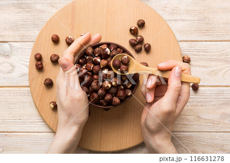Woman hands holding a wooden bowl with hazelnut nuts. Healthy food and snack. Vegetarian snacks of different nuts 116631278